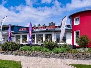 un restaurant aux drapeaux violets en face d'un bâtiment dans l'établissement Peterchens Mondfahrt - Wasserkuppe, à Gersfeld