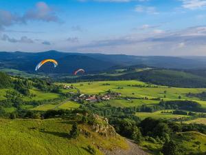 two paragliders are flying over a green field at Peterchens Mondfahrt - Wasserkuppe in Gersfeld