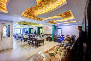 a restaurant with tables and chairs and people standing in a room at Hotel The North Wind in City Center, Manali in Manāli