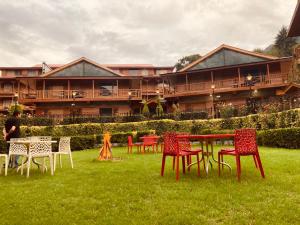 a group of tables and chairs in the grass in front of a building at Hotel The North Wind in City Center, Manali in Manāli