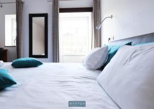 1 dormitorio con cama blanca con almohadas y espejo en MyStay - Casa Miná, en Montalegre