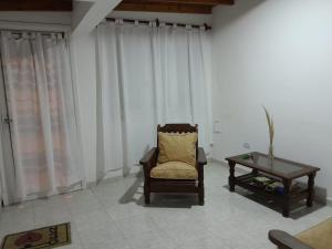 ein Wohnzimmer mit einem Stuhl und einem Tisch in der Unterkunft Casa Privada 2 habitaciones, amueblada Centro Necochea in Necochea