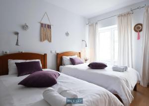 two beds in a bedroom with white and purple pillows at MyStay - Casa Miná in Montalegre