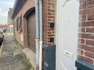 un bâtiment en briques avec une porte de garage dans une rue dans l'établissement Maison cosy 4 chambres proche toutes commodités, à Tourcoing