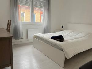 - un lit blanc dans une chambre blanche dotée d'une fenêtre dans l'établissement Maison cosy 4 chambres proche toutes commodités, à Tourcoing