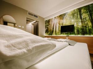 a bedroom with a large white bed with a tv on the wall at Park Hotel Sóstó in Nyíregyháza