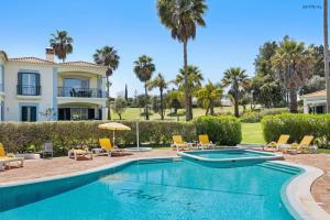 a villa with a swimming pool and palm trees at Pestana Carvoeiro Golfe - AL in Carvoeiro