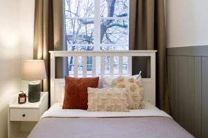 um quarto com uma cama branca com almofadas e uma janela em WAWELOVE spacious 3 bedroom apt 1 min to Main Sq! em Cracóvia