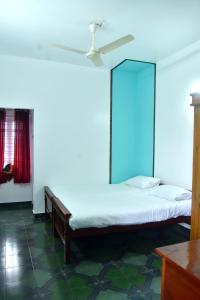 a bedroom with a bed with a ceiling fan at Suryas Rooms in Varkala