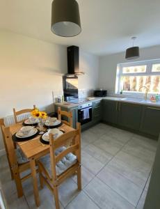 a kitchen with a wooden table and chairs in a kitchen at The Beautiful Bungalow Amazing location for Chester & Zoo in Wervin