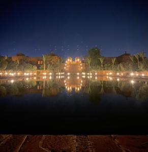 un bâtiment avec des lumières dans l'eau la nuit dans l'établissement Villa les oliviers, à Marrakech