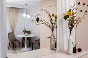 two white vases with flowers on a table at Est One Apartament 2 camere semidecomandat in Drobeta-Turnu Severin