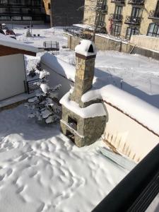 a snow covered patio with a stone fireplace at Bakuriani - Kokhta Gora in Bakuriani