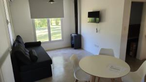 a living room with a table and a black couch at Cabañas El Rincon in Tandil