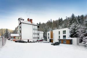 a building in the snow with cars parked at PARK APARTAMENTY Krynica Zdrój in Krynica Zdrój