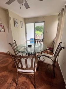 uma sala de jantar com uma mesa de vidro e 2 cadeiras em Country Paradise em Naguabo