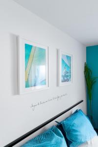 a bedroom with two pictures above a bed with blue pillows at Pupat in Marseille