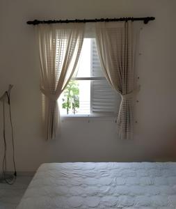 - une chambre avec un lit et une fenêtre avec des rideaux dans l'établissement Apartamento em Guarujá a 200 m da Asturias e Tombo, à Guarujá