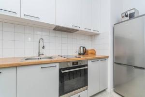 a white kitchen with a sink and a refrigerator at Zajezdnia Wrzeszcz by Grand Apartments in Gdańsk