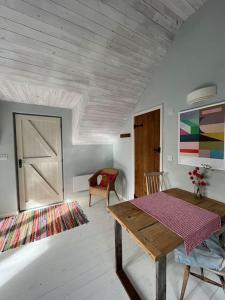 a living room with a wooden table and a couch at Bright, airy Annex in village with stunning views in Stroud