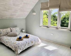 a bedroom with a bed and two windows at Bright, airy Annex in village with stunning views in Stroud