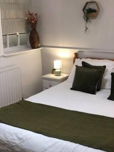 Beautiful 2 bedroom garden flat in great location في بريستول: غرفة نوم بسرير ابيض مع مخدات خضراء