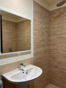 E25 Samarah Resort Apartments في السويمة: حمام مع حوض ومرآة