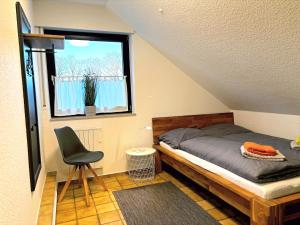 ein Schlafzimmer mit einem Bett und einem Stuhl und einem Fenster in der Unterkunft Ferienhaus Wacholderhain in Haselünne