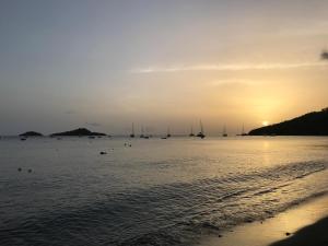 a sunset on the beach with boats in the water at Kaza Ohana proche de Malendure - maison 8 à 11 personnes in Bouillante