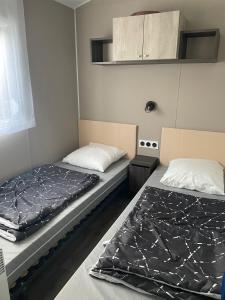 duas camas num pequeno quarto em Magnifique Mobilhome 3ch-2sdb-Clim Siblu Les Charmettes em Les Mathes