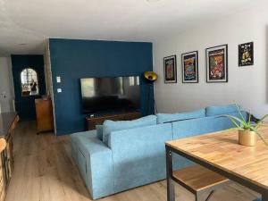 ein Wohnzimmer mit einem blauen Sofa und einem TV in der Unterkunft Location de charme in Le Haillan