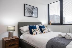 a bedroom with a bed with blue and white pillows at Pass the Keys Modern apartment - with parking in Manchester
