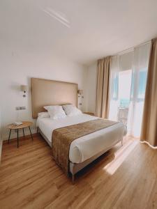 a bedroom with a large bed and a large window at FAY Victoria Beach in Rincón de la Victoria