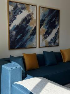 a living room with a blue couch and two paintings at Luxury Apartment Downtown Dubai Mall Burj Khalifa View free Netflix & Prime Video in Dubai