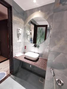 a bathroom with a sink and a mirror at Hotel The Excellency in Surat