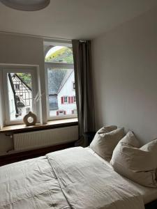 a bedroom with a white bed and a window at Urige Dachgeschosswohnung, liebevoll renoviert in Ürzig