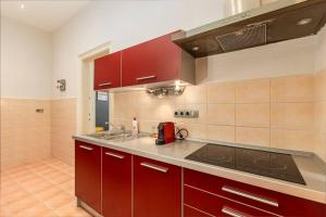 a kitchen with red cabinets and a stove top oven at Bold Base Apartment in Budapest