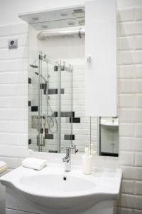 W białej łazience znajduje się umywalka i lustro. w obiekcie Bold Base Apartment w Budapeszcie
