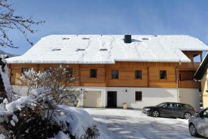 uma grande casa de madeira com neve no telhado em Stranach Appartements em Sankt Michael im Lungau