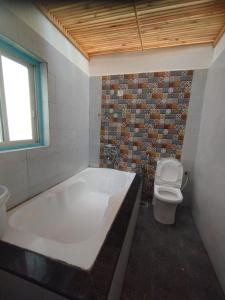 a bathroom with a large tub and a toilet at The Baga Village-TBV in Baga