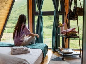 Una chica sentada en una habitación mirando por una ventana en Focus Point Drakhtik - Green Cabin en Drakhtik