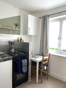 a kitchen with a stove and a table with a chair at Comfortable and convenient 1-Bed Apart in Romford in Romford