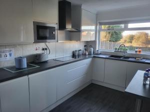 a kitchen with white cabinets and a sink and a window at Almost Heaven in Acton Trussell