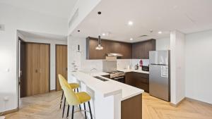 a kitchen with a white counter and yellow chairs at Exceptional 1 BR next to Dubai Metro and World Trade Center Dubai by GP Holiday Homes in Dubai