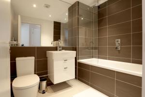 a bathroom with a toilet and a tub and a sink at Barbican Serviced Apartments in London