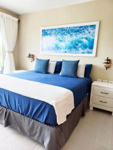 a bedroom with a large bed with blue and white pillows at Vibe Residence Dominicus in Bayahibe