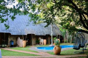 a house with a thatched roof and a swimming pool at Nguni Lodge in Victoria Falls