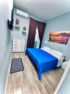 a bedroom with a blue bed and a window at Rodinó rooms in Naples