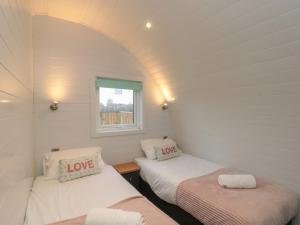 two beds in a small room with a window at Sunset Gem in Burton Fleming