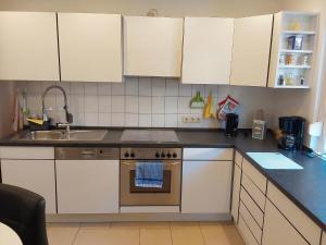 a kitchen with white cabinets and a stove and a sink at Fewo Rosi in Brotterode